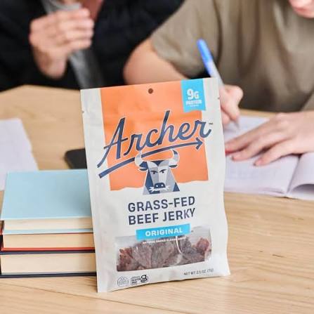 Archer grass-fed beef jerky: person holding a bag of beef jerky at a table