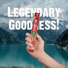 Righteous Felon O.G. Hickory beef sticks: wrapped beef stick held against an outdoor background