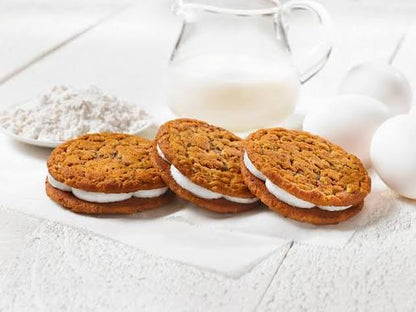 Little Debbie Oatmeal Creme Pies served beside milk and oats.
